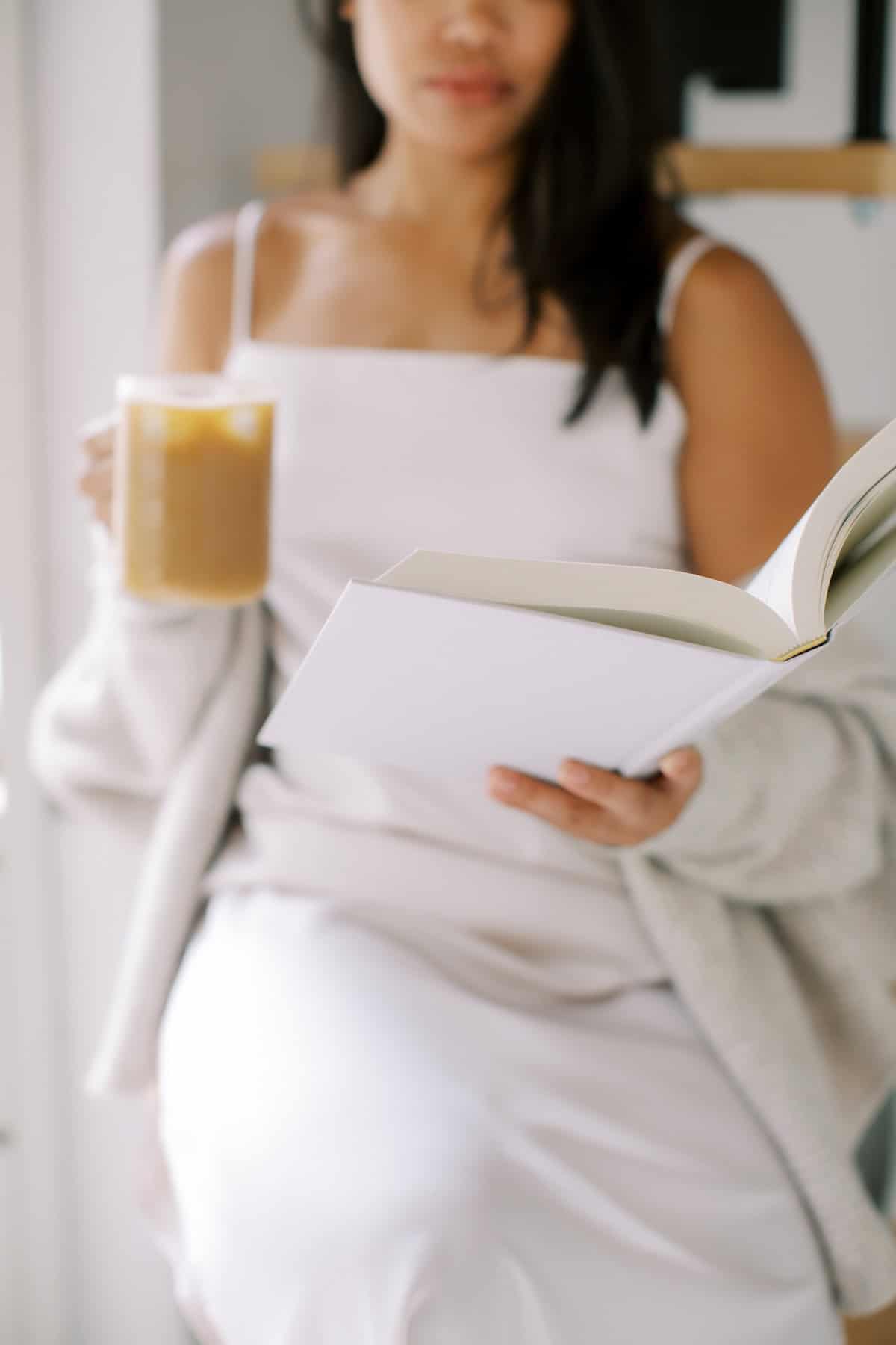 Woman in soft loungewear reading a book and sipping coffee during a quiet, screen-free Sunday morning.