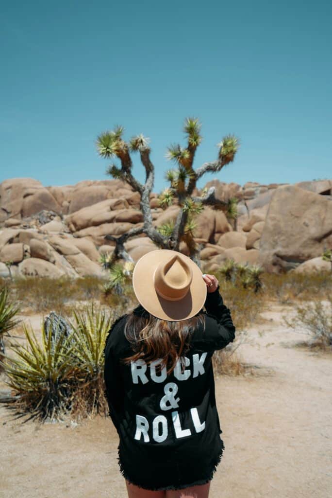 A woman standing in the desert facing a cactus, using nature and solitude as grounding ways to relax when stressed.