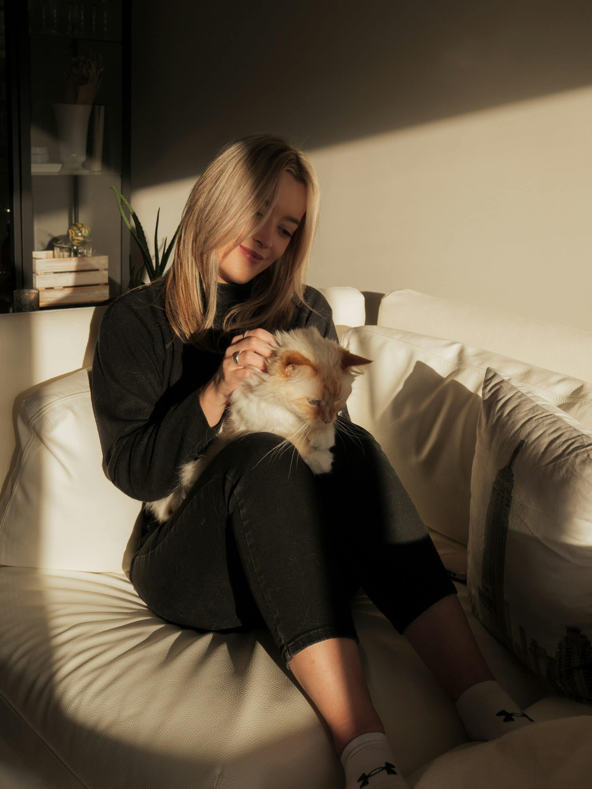 Woman calming ADHD overwhelm by grounding with her cat in cozy sunlight.