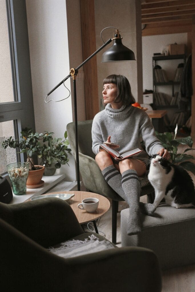 Woman journaling with coffee and cat — taking a mindful break from ADHD decision fatigue.