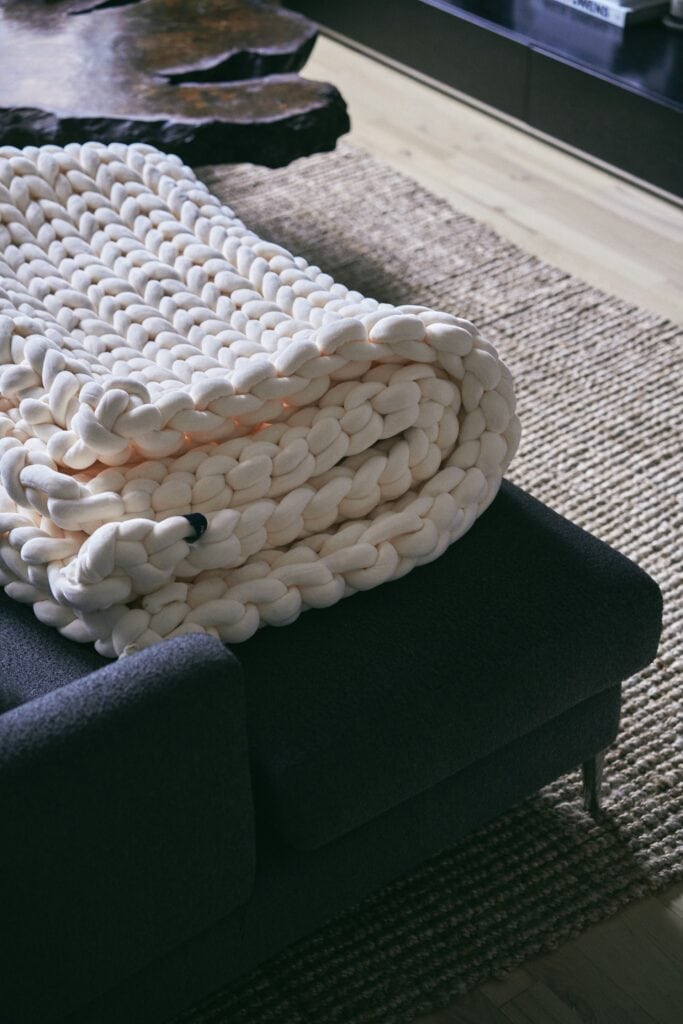A chunky knit blanket folded on a sofa, showing an easy sensory comfort that helps ADHD homes feel calmer.