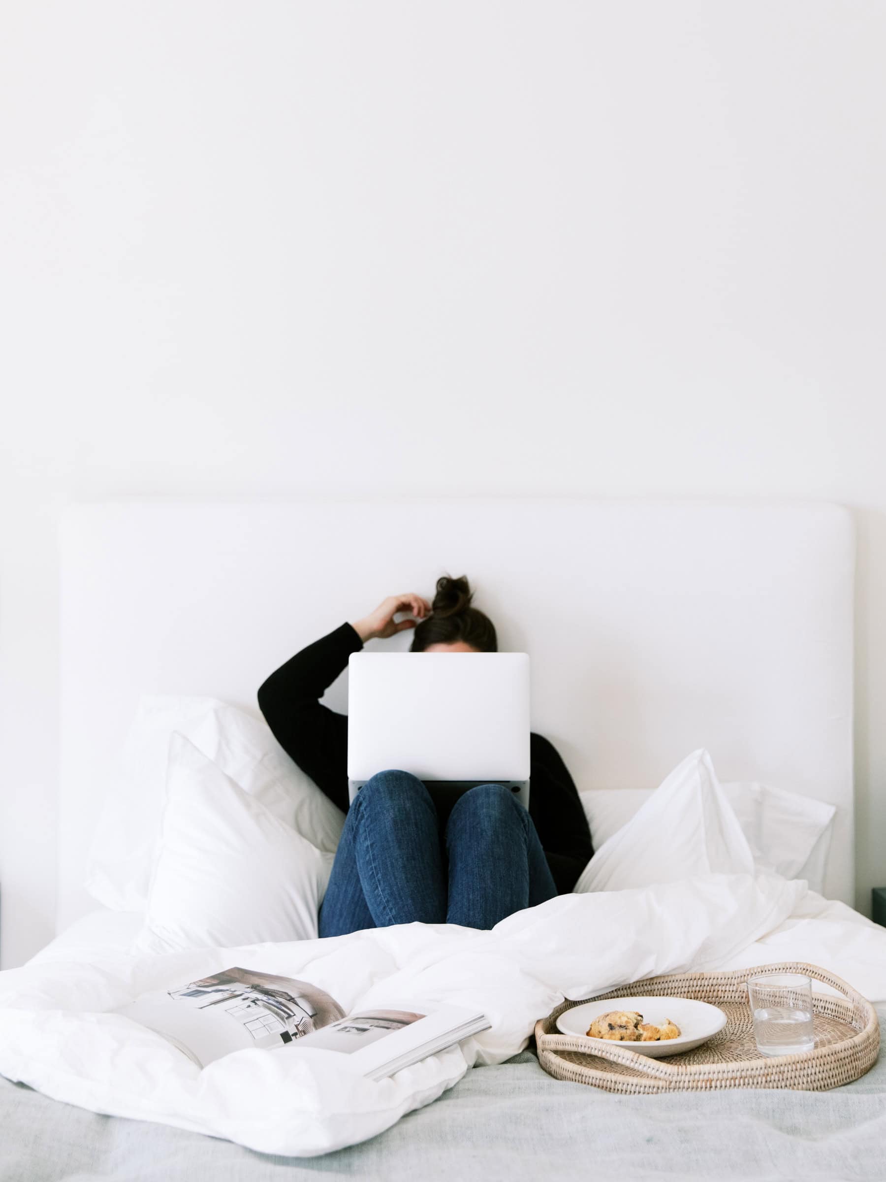 Person sitting up in bed with a laptop while sick, showing how being sick with ADHD and living alone requires managing tasks with very low energy.
