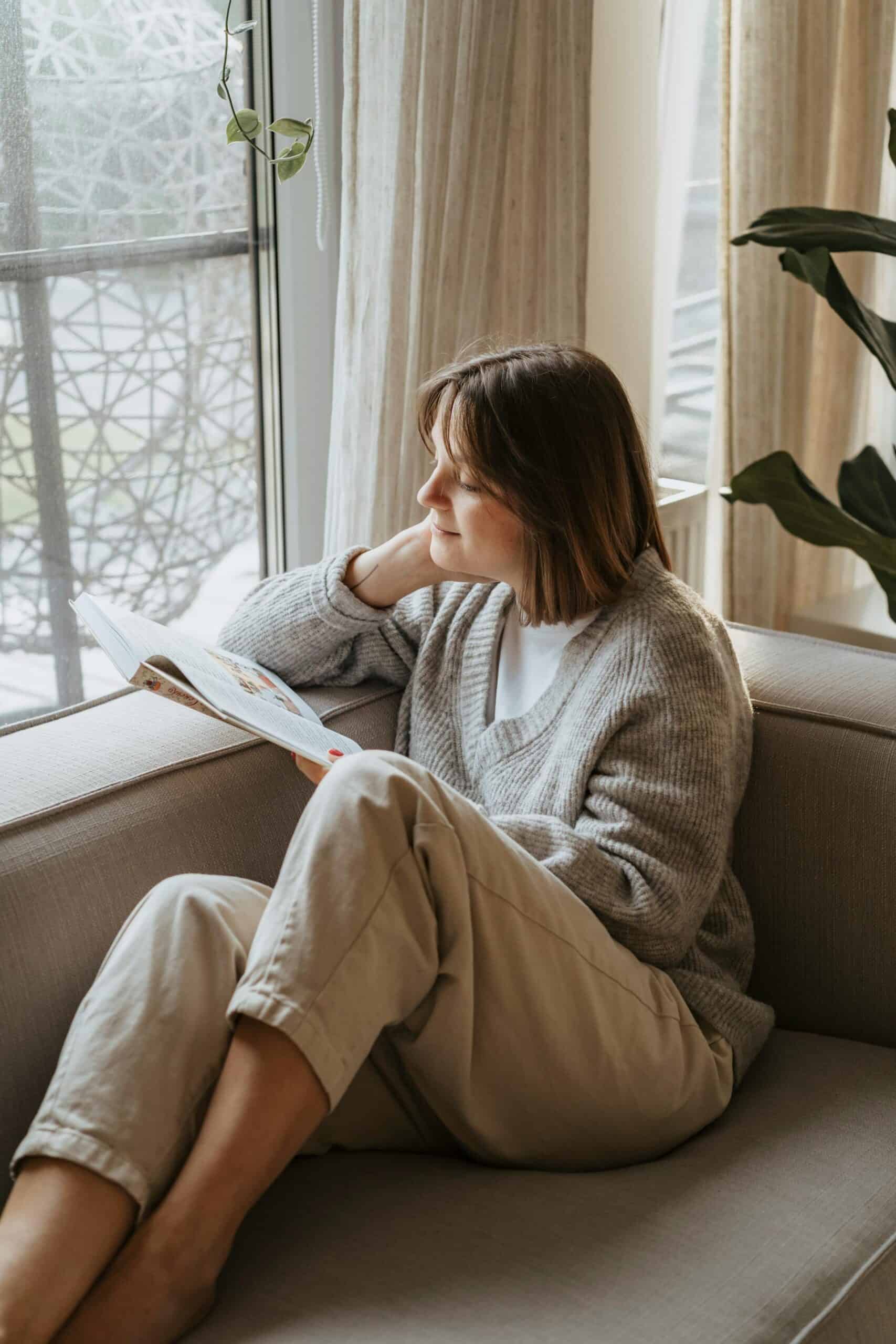 woman sitting by window reading and resting after an ADHD errand recovery routine