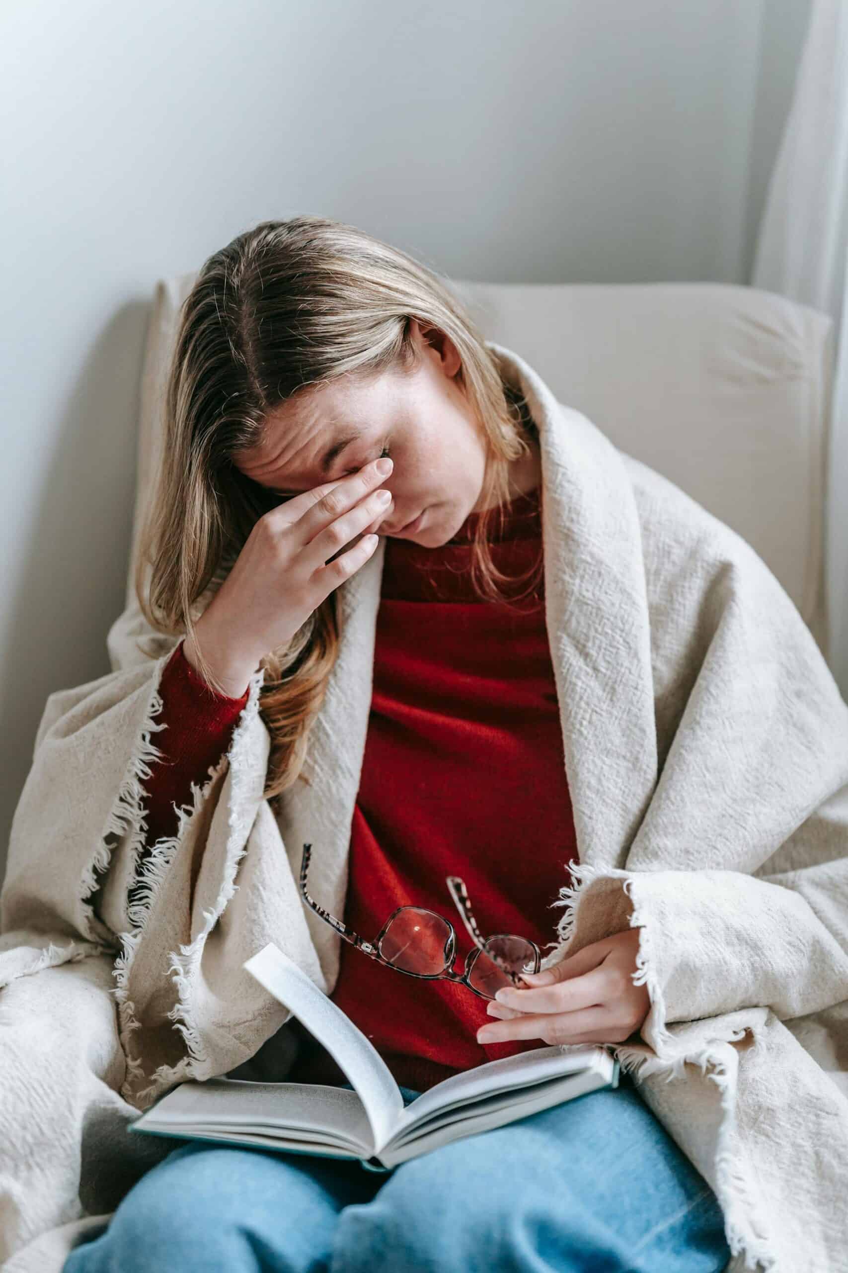 woman feeling overwhelmed during ADHD overstimulation while sitting under a blanket at home